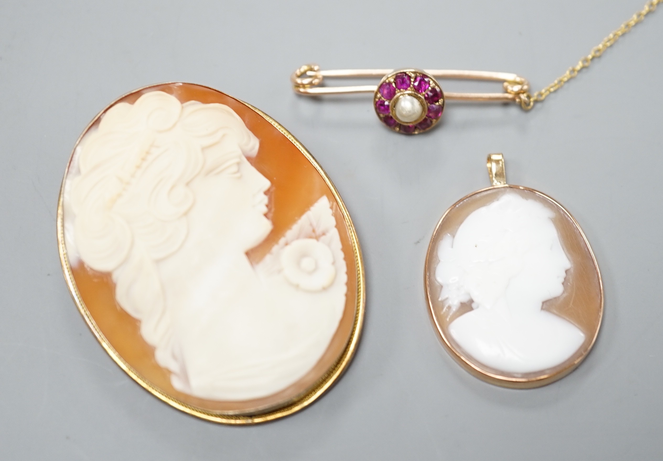 A 9ct mounted oval cameo shell pendant, 36mm, a similar gilt white metal mounted brooch and a yellow metal, ruby and cultured pearl cluster set bar brooch(converted).